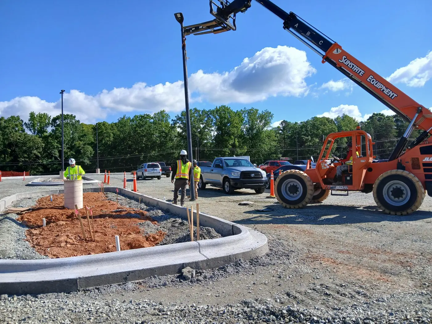 Light pole being lowered onto its base in a new paved lot